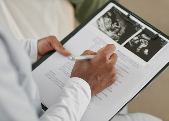 Doctor reviewing fetal ultrasound images and medical reports during an obstetrics and gynaecology consultation.