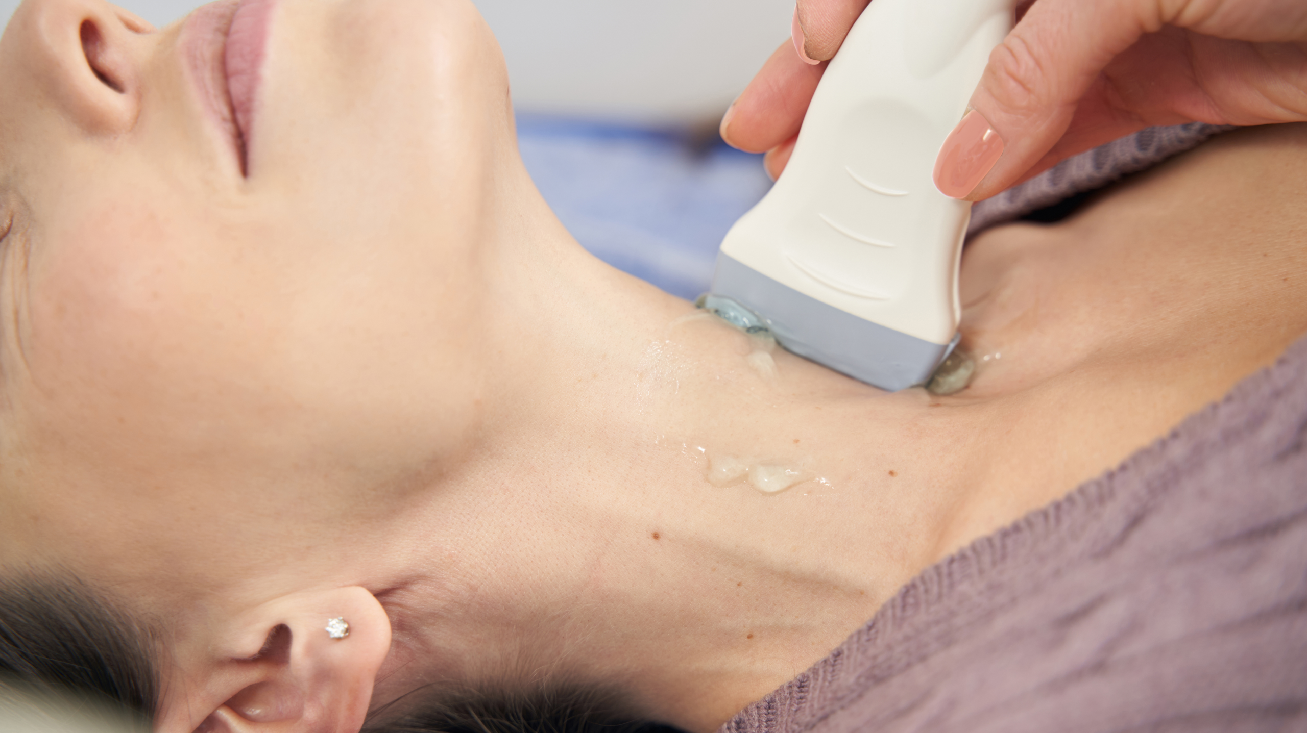 Ultrasound examination of the neck area during a diagnostic imaging procedure in a medical clinic.