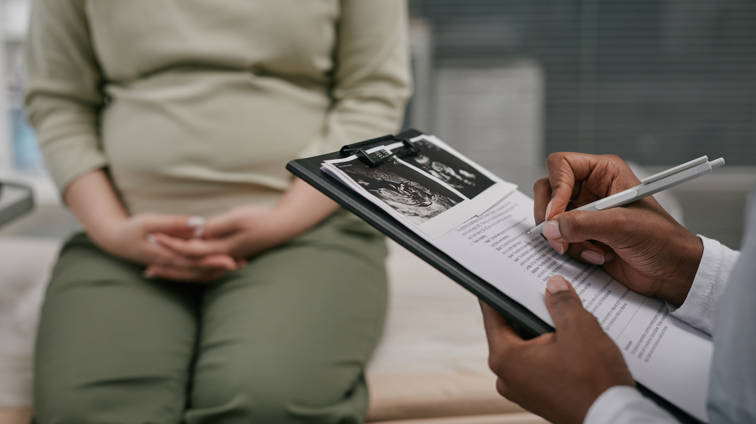 Doctor reviewing pregnancy ultrasound reports with an expectant mother during an obstetrics and gynaecology consultation.