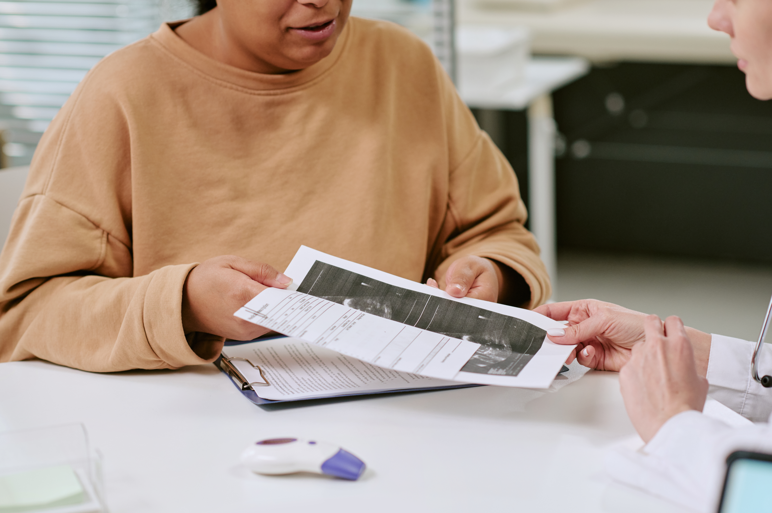 Doctor discussing medical reports and scan results with a patient during a healthcare consultation.